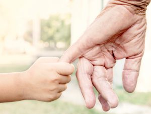 Image of a young child holding and older persons finger